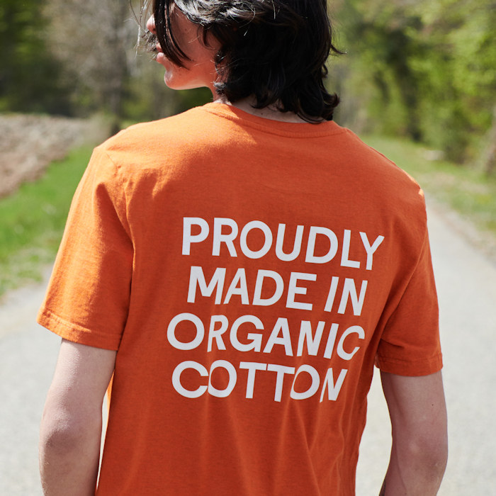 Man in an orange organic cotton t-shirt with an eco-friendly message printed on the back.